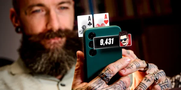 Poker player holding a smartphone with pocket aces
