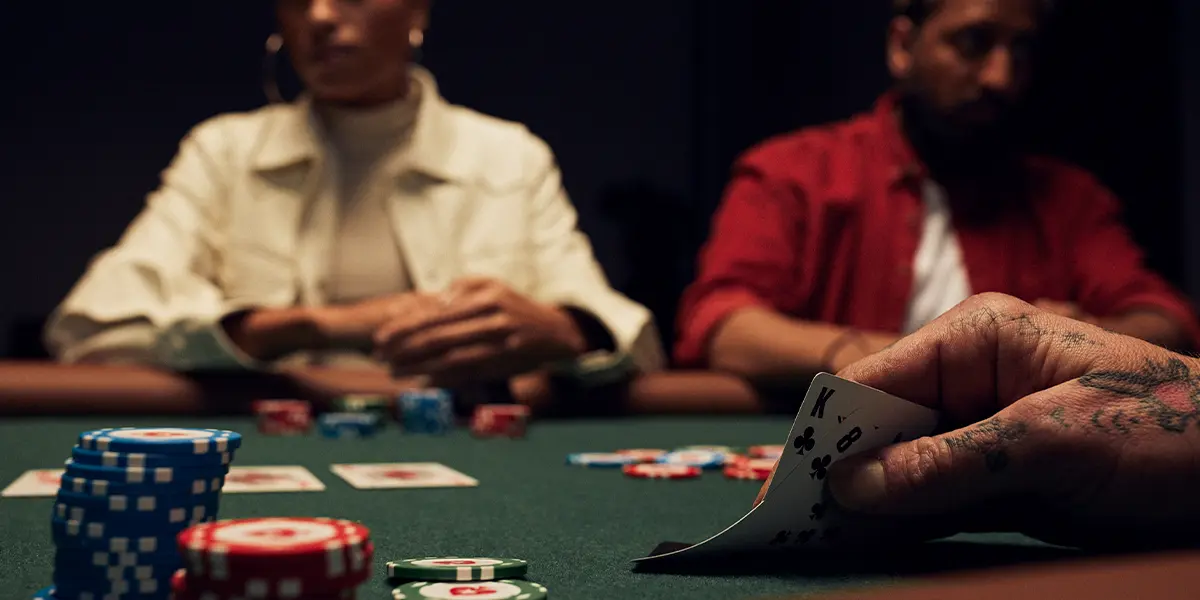 A poker player contemplating a bluff-catch on the river, focusing on card removal and blocker effects with a weak kicker.