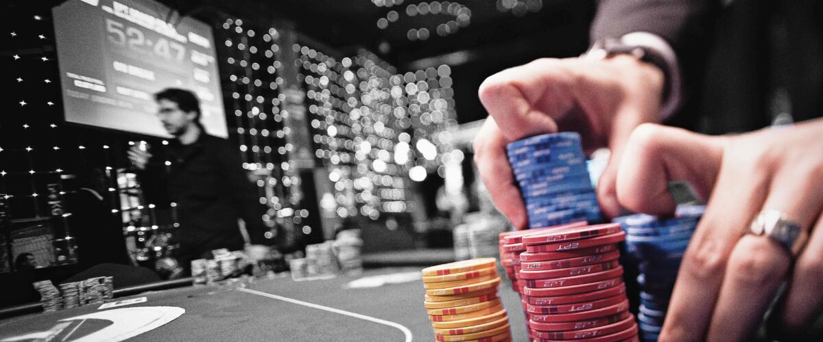 A poker dealer collects different coloured poker chips from the table.