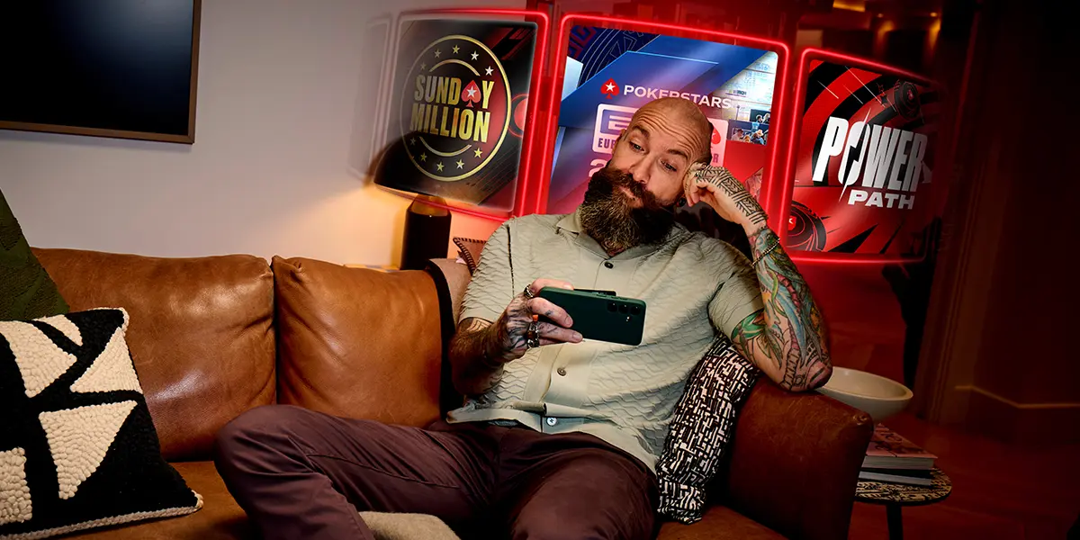 A player reviewing the PokerStars tournament lobby on a mobile device while relaxing at home.